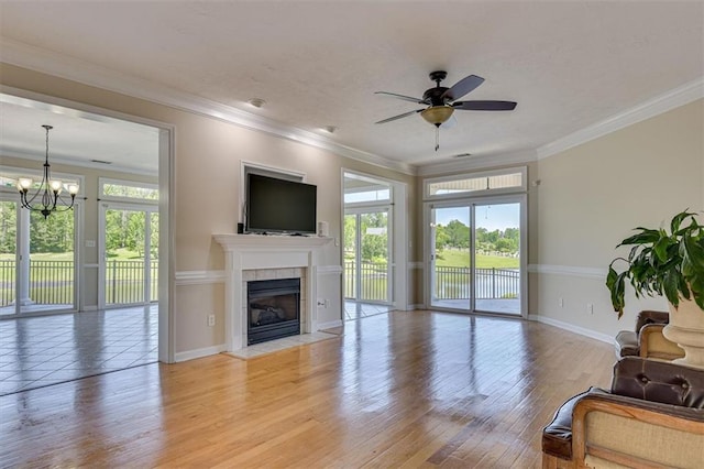 living area with a chandelier, baseboards, a fireplace, ceiling fan, and light wood-style floors