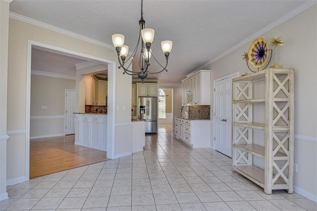 kitchen featuring stainless steel fridge, a chandelier, backsplash, light tile patterned floors, and crown molding