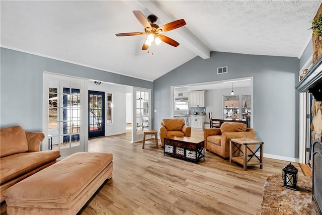 living room featuring vaulted ceiling with beams, light wood-type flooring, ceiling fan, a textured ceiling, and french doors