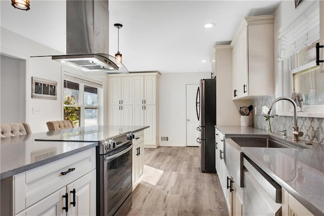 kitchen with pendant lighting, light hardwood / wood-style flooring, appliances with stainless steel finishes, tasteful backsplash, and island exhaust hood