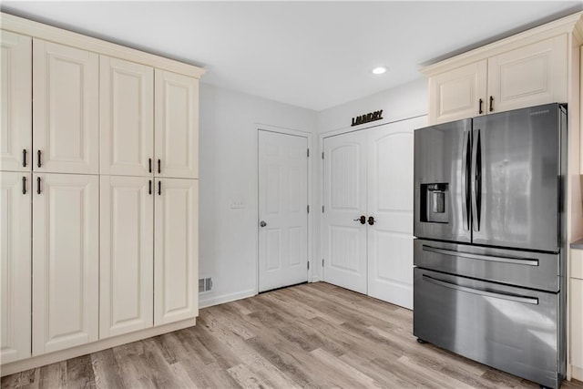 kitchen featuring stainless steel refrigerator with ice dispenser, cream cabinetry, and light hardwood / wood-style flooring