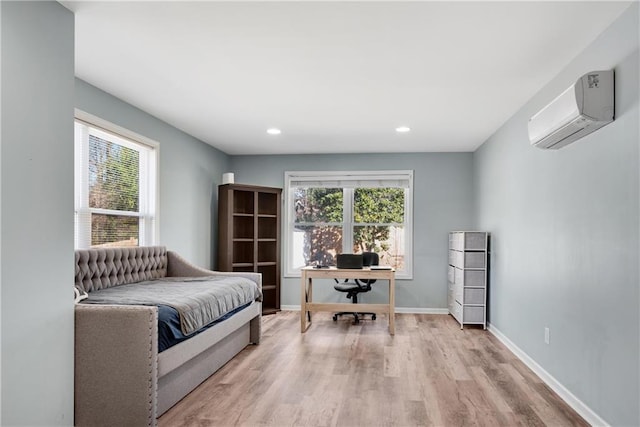 bedroom with multiple windows, a wall unit AC, and light hardwood / wood-style flooring