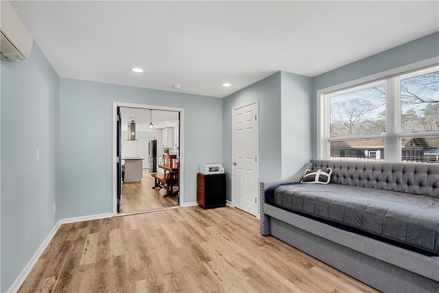 living area with a wall mounted air conditioner and light hardwood / wood-style flooring