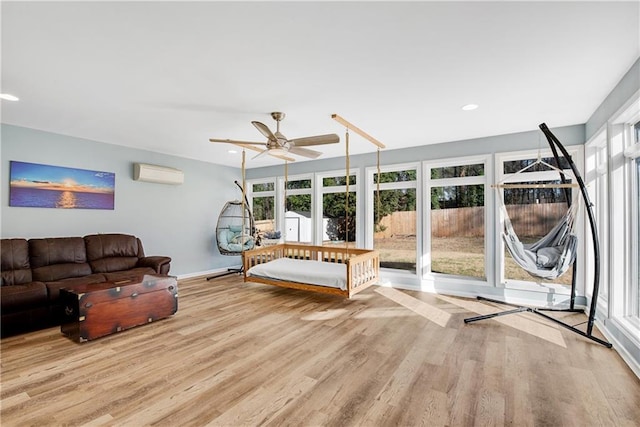 unfurnished living room with an AC wall unit, ceiling fan, and light hardwood / wood-style flooring