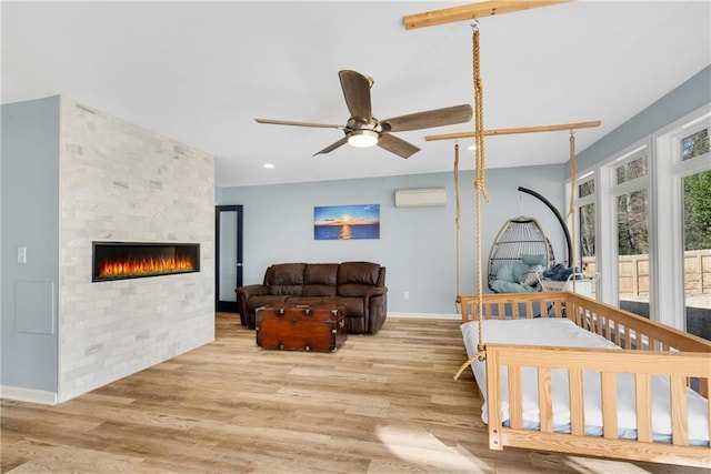 bedroom featuring a wall mounted air conditioner, a fireplace, and light hardwood / wood-style floors