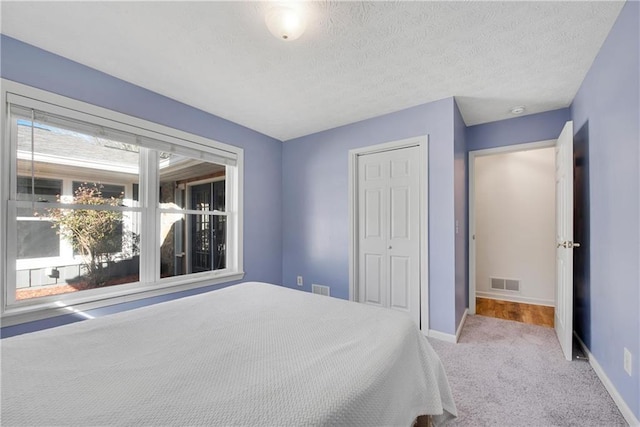 unfurnished bedroom featuring light colored carpet, a closet, and a textured ceiling