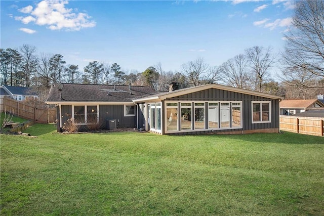 rear view of property featuring central AC unit and a lawn