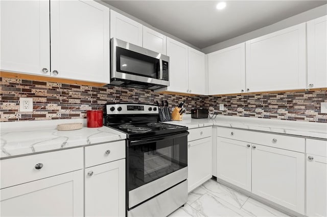 kitchen with marble finish floor, stainless steel appliances, light stone counters, and decorative backsplash