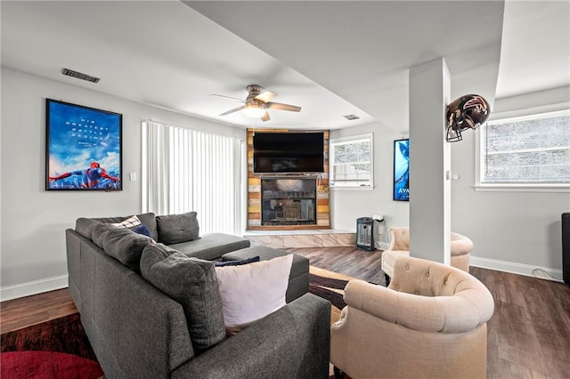 living room with baseboards, a fireplace, visible vents, and wood finished floors