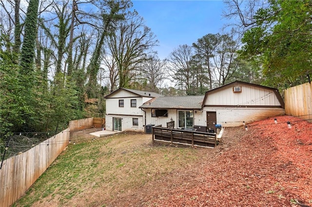 rear view of property featuring a deck, a fenced backyard, central AC, brick siding, and a yard