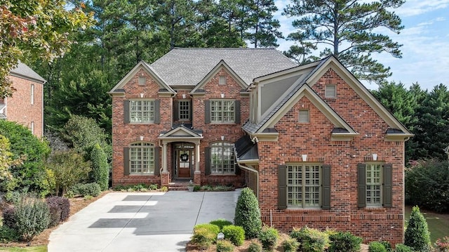 view of front of home featuring brick siding and roof with shingles