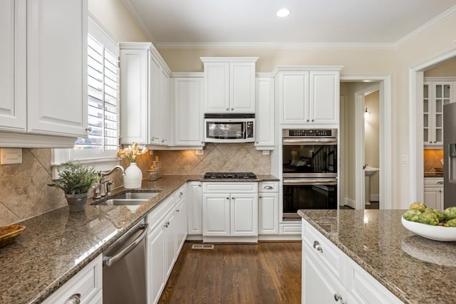 kitchen featuring a sink, white cabinetry, appliances with stainless steel finishes, dark wood finished floors, and crown molding