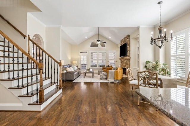 interior space featuring stairway, ceiling fan with notable chandelier, wood finished floors, and a stone fireplace