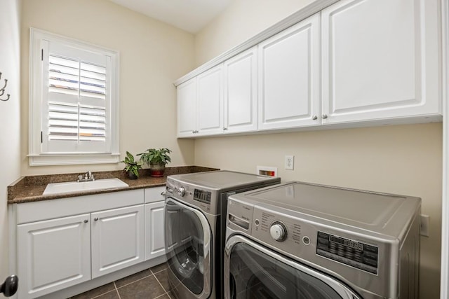 clothes washing area with cabinet space, washing machine and dryer, a sink, and dark tile patterned floors