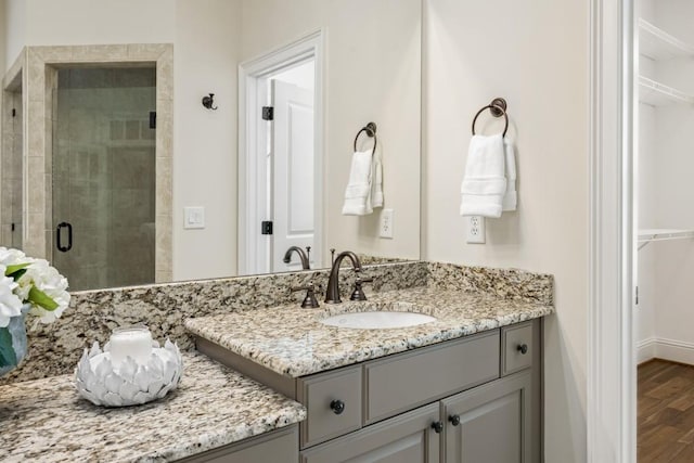 bathroom with a stall shower, a spacious closet, vanity, and wood finished floors