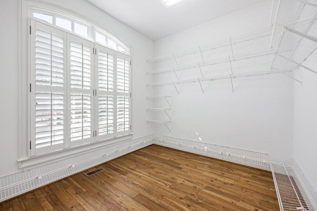 empty room featuring hardwood / wood-style floors, visible vents, and a healthy amount of sunlight