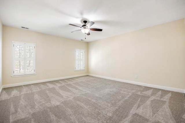 spare room featuring a wealth of natural light, carpet, visible vents, and baseboards