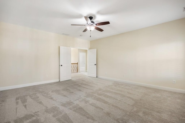 empty room featuring a ceiling fan, light carpet, visible vents, and baseboards