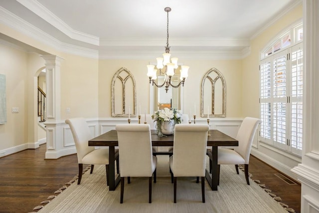 dining room with arched walkways, a notable chandelier, wood finished floors, stairs, and ornamental molding