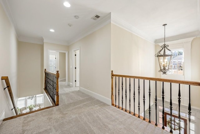 hallway with a chandelier, carpet flooring, visible vents, an upstairs landing, and ornamental molding