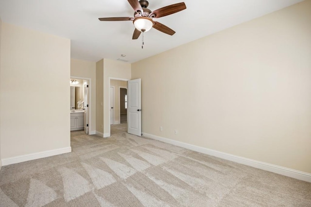 unfurnished bedroom with light carpet, baseboards, a ceiling fan, and ensuite bathroom