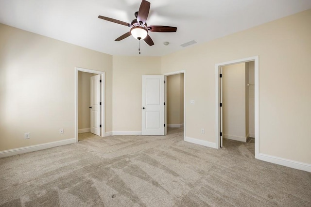 unfurnished bedroom featuring carpet floors, visible vents, a spacious closet, and baseboards