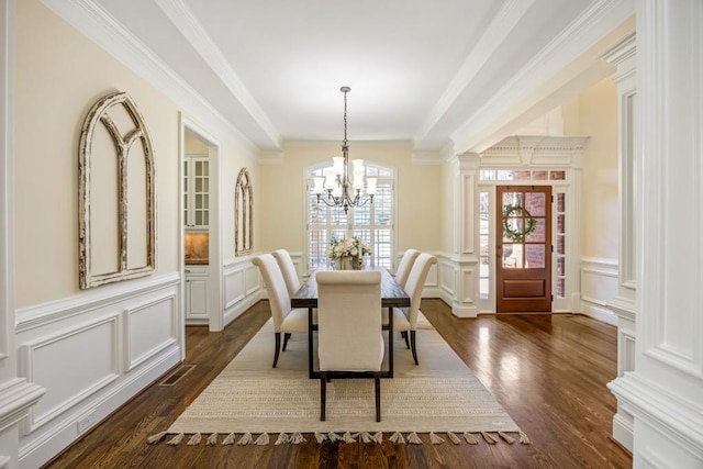 dining space featuring a chandelier, visible vents, a decorative wall, and ornate columns