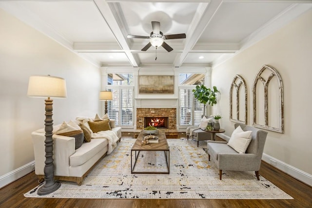 living area with baseboards, coffered ceiling, beamed ceiling, wood finished floors, and a stone fireplace