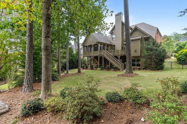 rear view of house featuring a chimney, a lawn, fence, a deck, and stairs