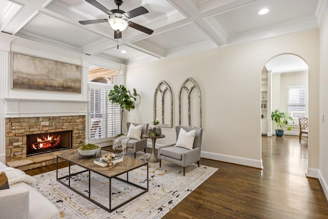 living area featuring arched walkways, dark wood-style flooring, coffered ceiling, and baseboards