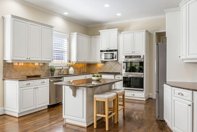 kitchen featuring white cabinets, dark wood-style floors, a breakfast bar, stainless steel appliances, and a sink