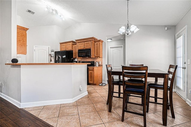 kitchen featuring visible vents, brown cabinetry, lofted ceiling, an inviting chandelier, and black appliances