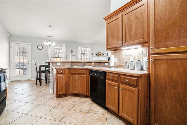 kitchen featuring a peninsula, a sink, light countertops, black appliances, and tasteful backsplash