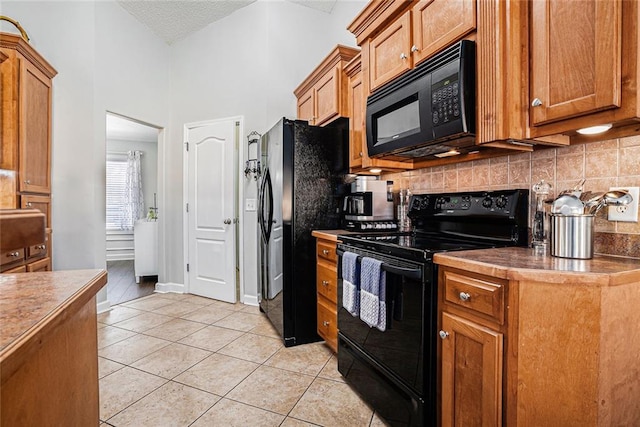 kitchen featuring decorative backsplash, brown cabinets, black appliances, and light tile patterned floors