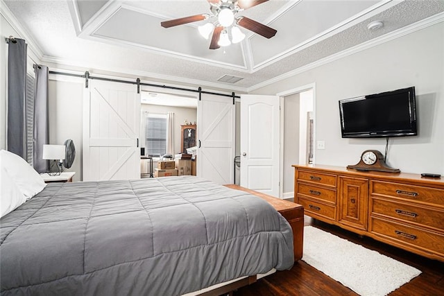 bedroom featuring a barn door, dark wood-type flooring, crown molding, and a raised ceiling