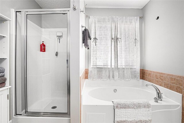 full bathroom featuring a stall shower, a textured ceiling, and a bath