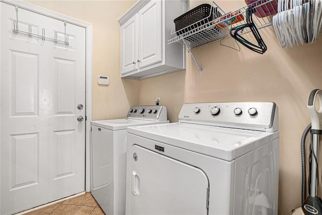 laundry area with light tile patterned floors, washing machine and dryer, and cabinet space