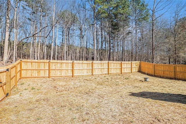 view of yard with a fenced backyard and a view of trees