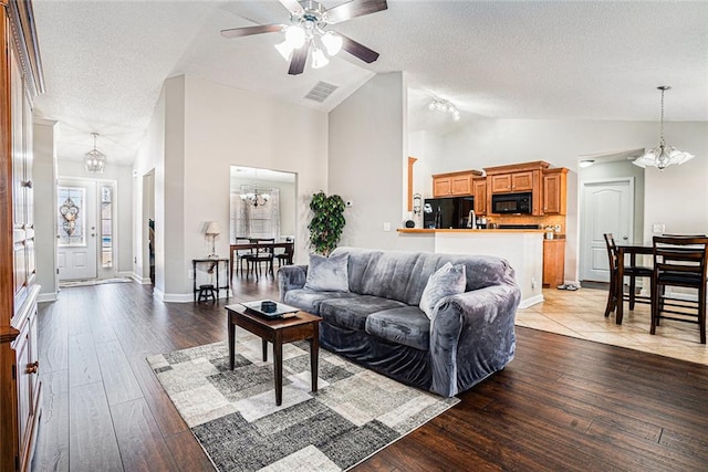 living room with visible vents, wood-type flooring, a textured ceiling, high vaulted ceiling, and ceiling fan with notable chandelier