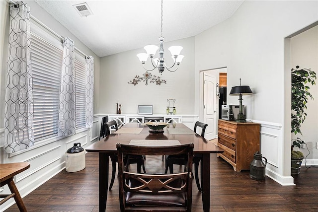 dining space with a chandelier, dark wood-style flooring, vaulted ceiling, and a decorative wall