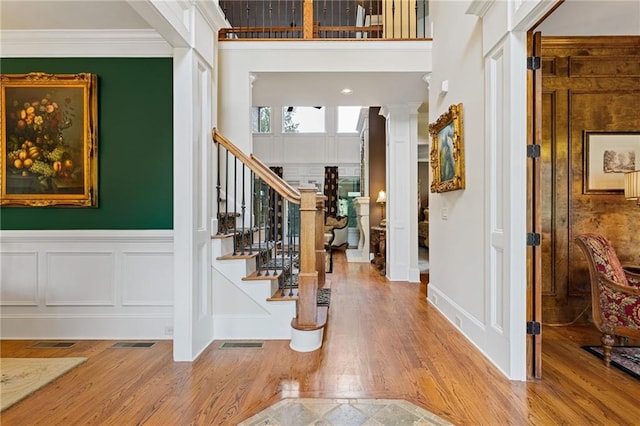 entrance foyer featuring decorative columns, hardwood / wood-style floors, and crown molding