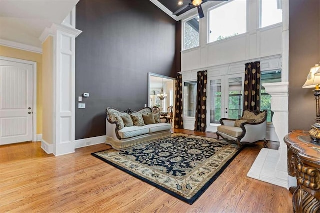 living room with ornamental molding, a towering ceiling, hardwood / wood-style floors, and a healthy amount of sunlight