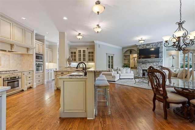 kitchen with light wood-type flooring, a fireplace, decorative light fixtures, and cream cabinetry