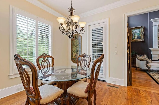 dining space with ornamental molding, a chandelier, and light hardwood / wood-style floors