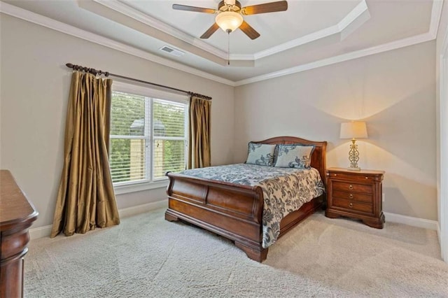 carpeted bedroom with crown molding, a tray ceiling, and ceiling fan