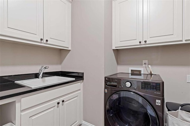 clothes washing area with washer / clothes dryer, sink, and cabinets