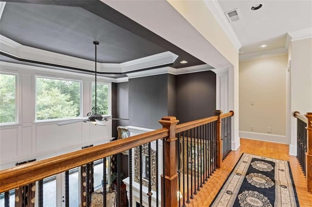 hall featuring a tray ceiling, crown molding, and light hardwood / wood-style floors