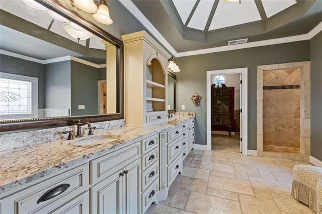 bathroom featuring ornamental molding, tiled shower, vanity, and a skylight