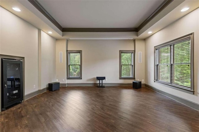 unfurnished living room with crown molding, dark hardwood / wood-style flooring, and a raised ceiling