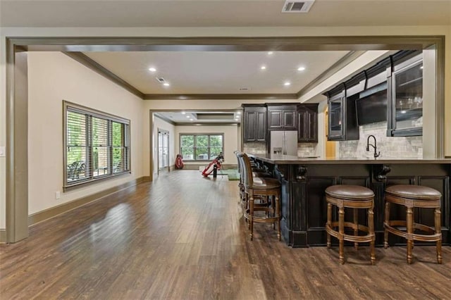 interior space with white refrigerator with ice dispenser, kitchen peninsula, a breakfast bar area, dark hardwood / wood-style floors, and sink